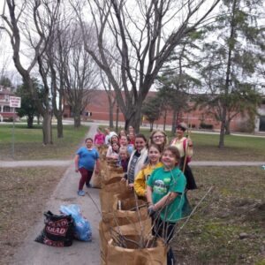 Young children lineup on a path with their filled brown yard bags for a photo in a park near a school