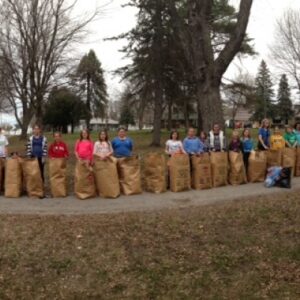 Group of young children line up on a path with their filled brown yard bags in a park area