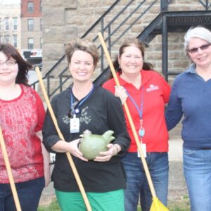 Four women standing with rakes and smiling for a photo